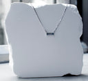 Bar None baguette sapphire necklace in 14K white gold shown front-on against a white stone block, highlighting the east-west sapphire pendant and faceted bar-link chain.