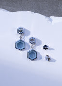 The Hex Effect earrings in 18K white gold shown from the front with velvety blue hexagonal Montana sapphire slabs, hexagon diamond tops and custom friction backs beside them.