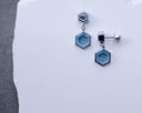 The Hex Effect earrings in 18K white gold shown from the front and side, with hexagonal Montana sapphire drops and hexagon diamond tops.
