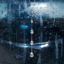 Lariat necklace with five pear-shaped stones displayed against a blue plastic water jug with condensation inside.