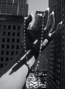 Old mine cut diamond necklace with slim bar links held in a hand overlooking Rockefeller Plaza in NYC.