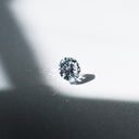 Loose round brilliant cut diamond photographed in natural sunlight on a white background.