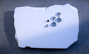 Finished pair of The Hex Effect geometric drop earrings with Montana sapphire slabs and hexagon diamonds on a white slab.